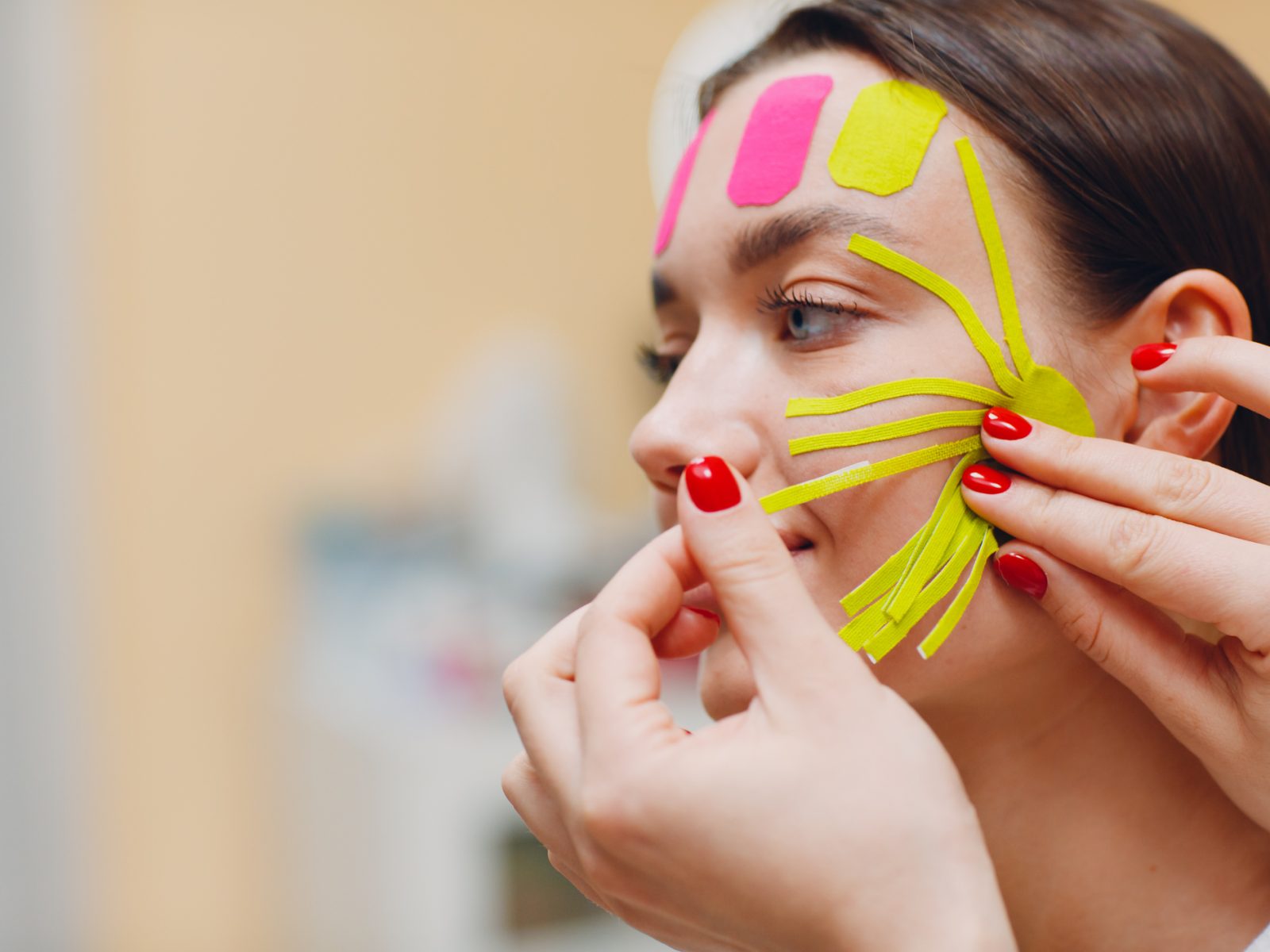 Beautiful woman applying tape lifting treatment procedure on face