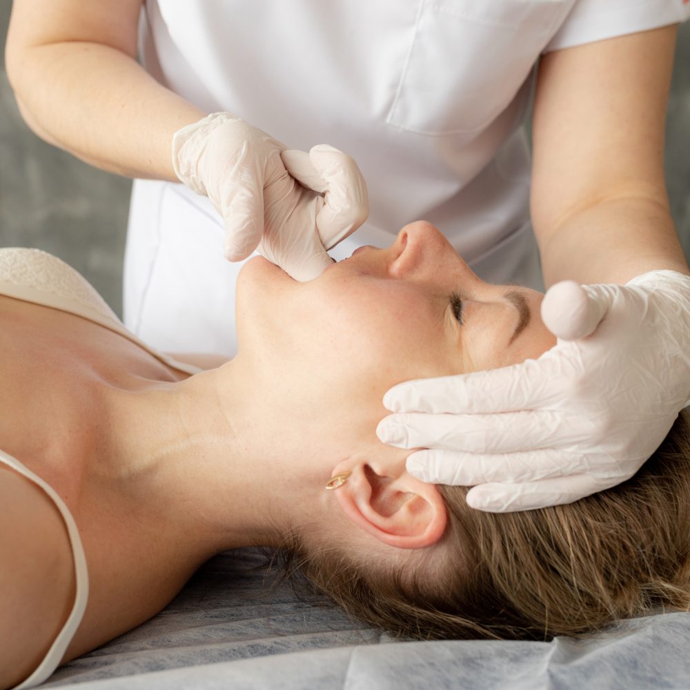 Female doctor physiotherapist, chiropractor, osteopath doing anti wrinkle manual myofascial face muscles massage with fingers in the mouth. Palpating of face, Skin and body care. Cosmetology service